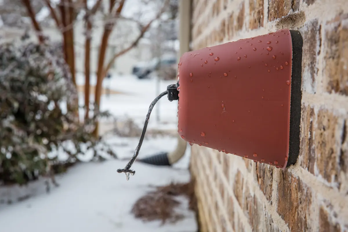 Insulated cover on an outdoor faucet with icicles hanging from it after a winter storm